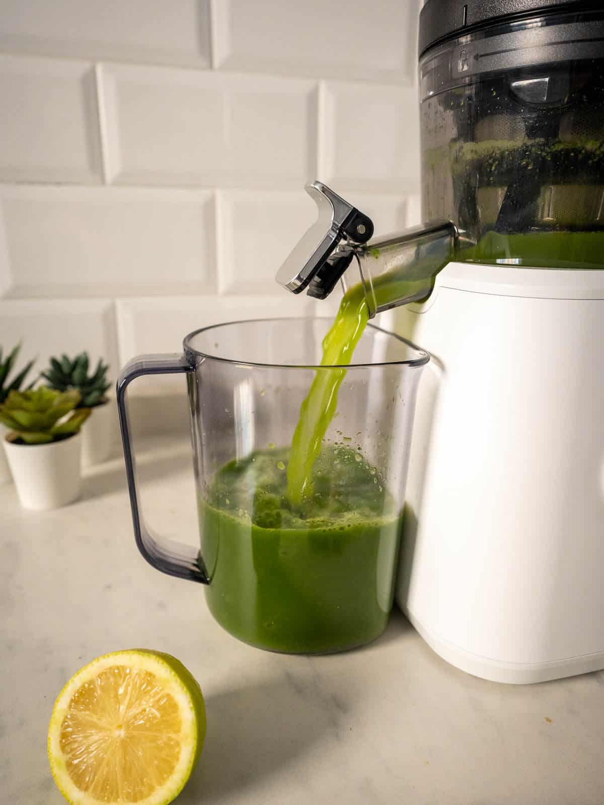 pouring green apple juice from juicer.