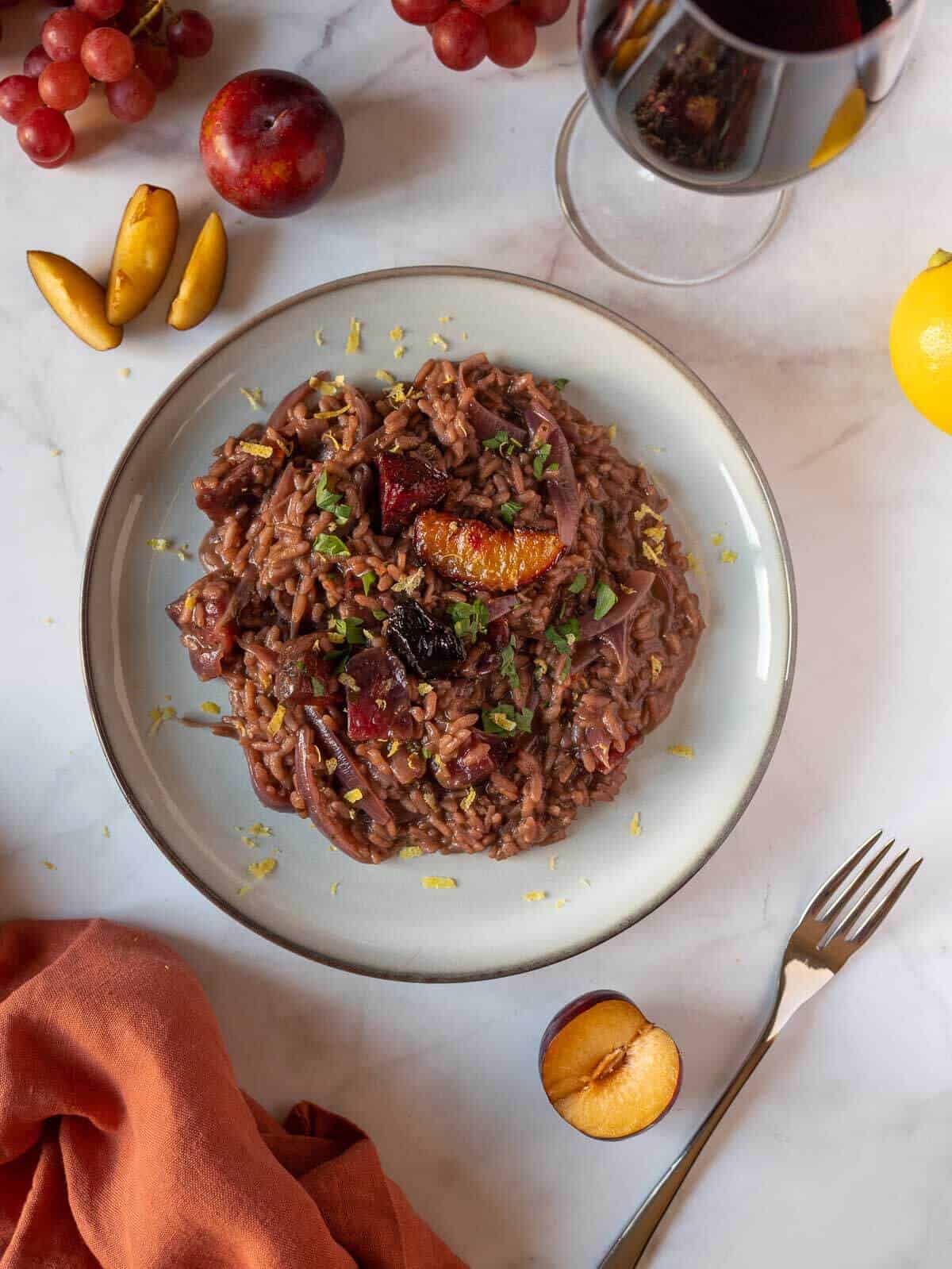 red wine risotto plated with a glass of red wine.