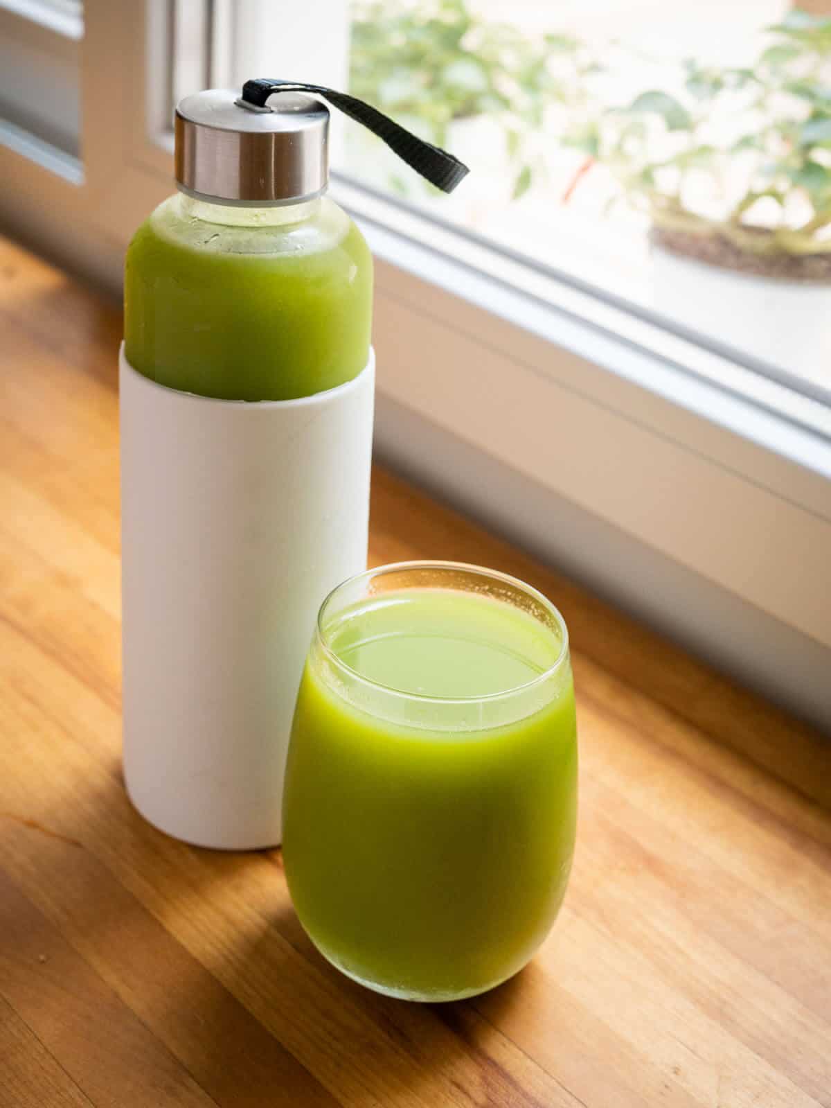 celery juice glass and a container with stored celery juice.