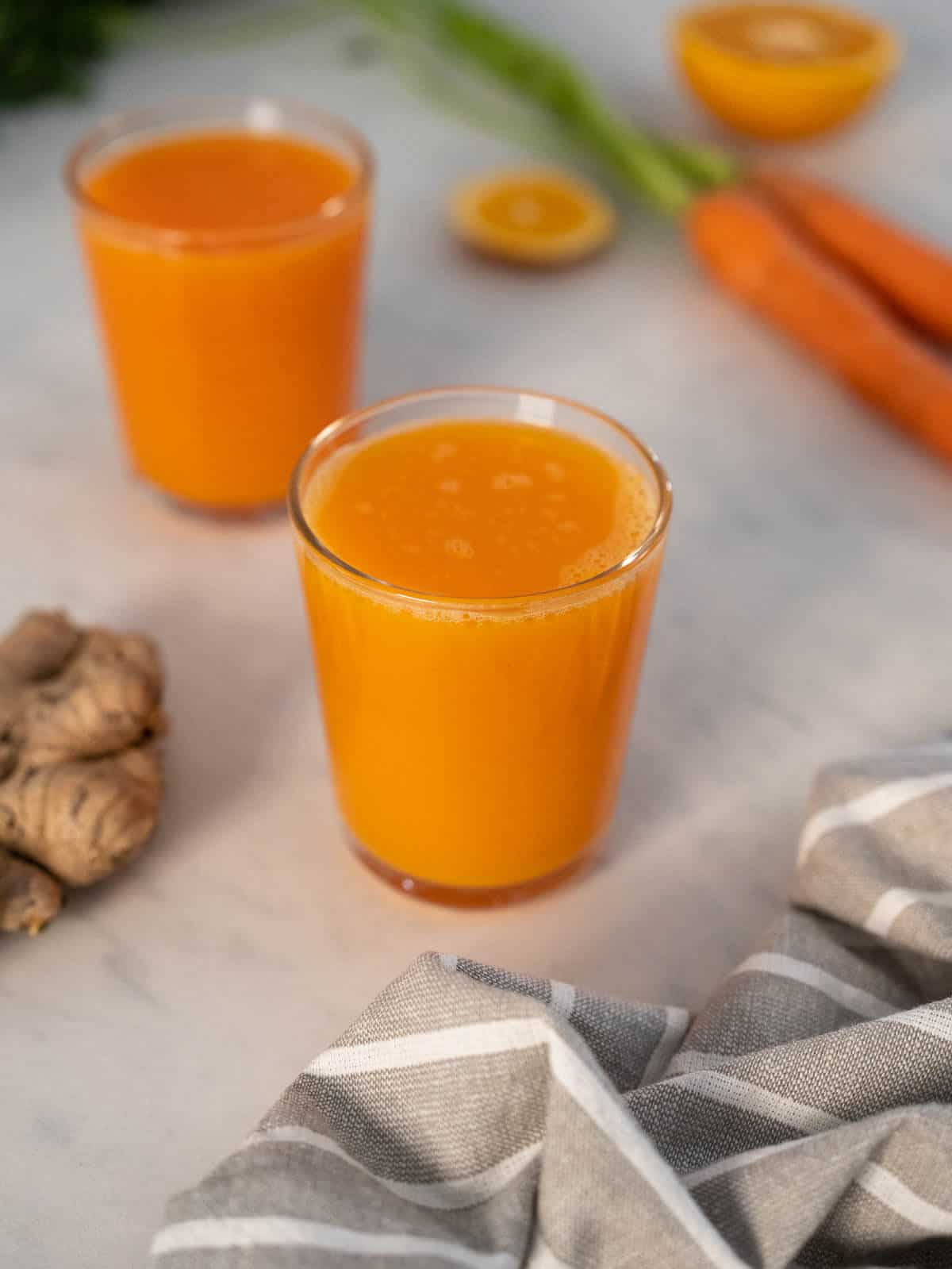 two glasses fresh carrot orange ginger juice.