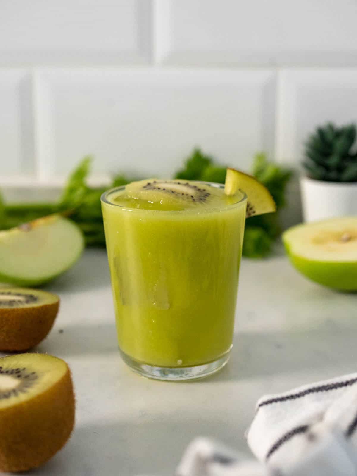 kiwi drink served ina. glass with kiwi halves on a table.