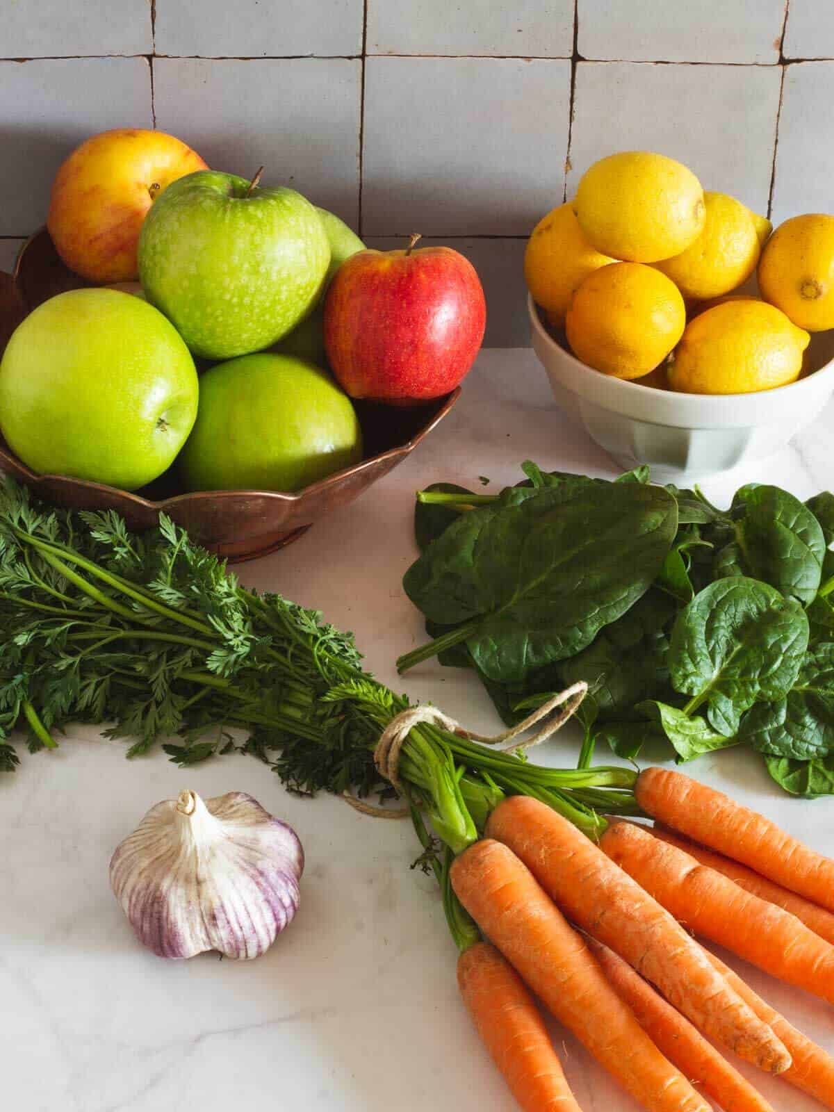 fresh produce including apples lemons carrots spinach and garlic.