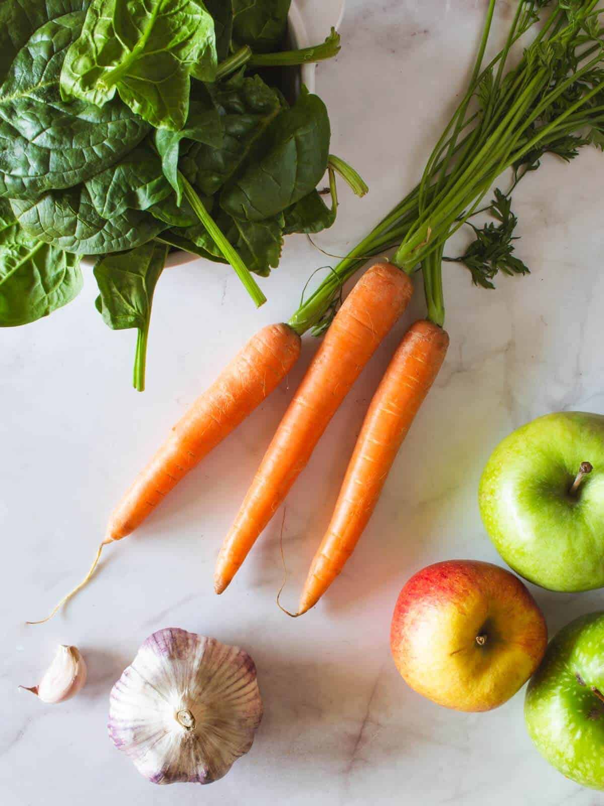 ingredients to make apple lemon carrot spinach juice shots.