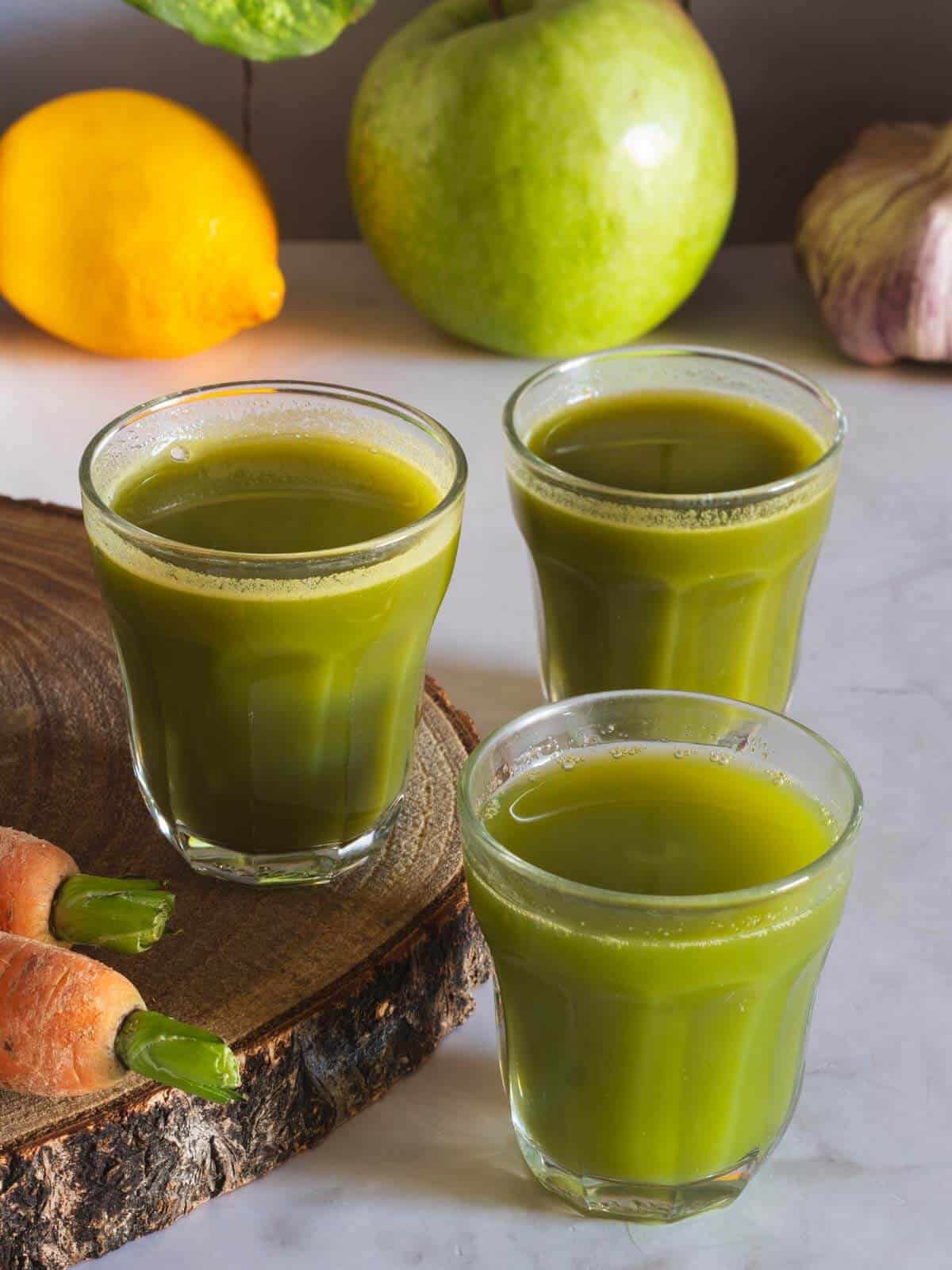 three apple lemon carrot spinach juice shots.