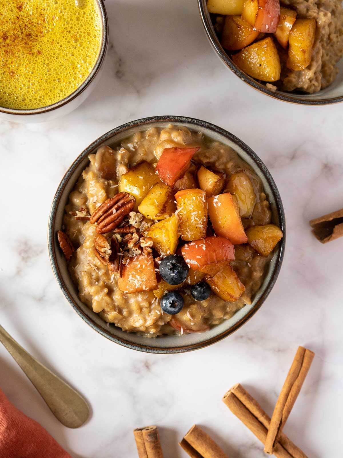 bowl of brown sugar cinnamon oatmeal next to a cup of golden milk.