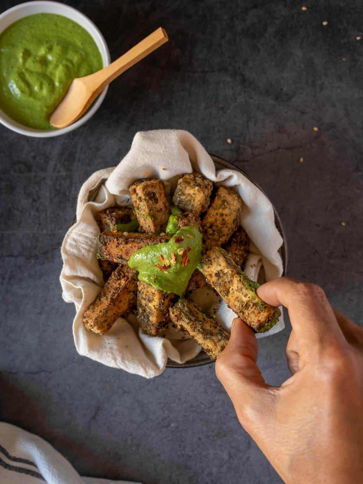 dipping air fried tofu in a sauce.