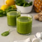 two glasses of pineapple ginger juice with spinach and cucumber featured.