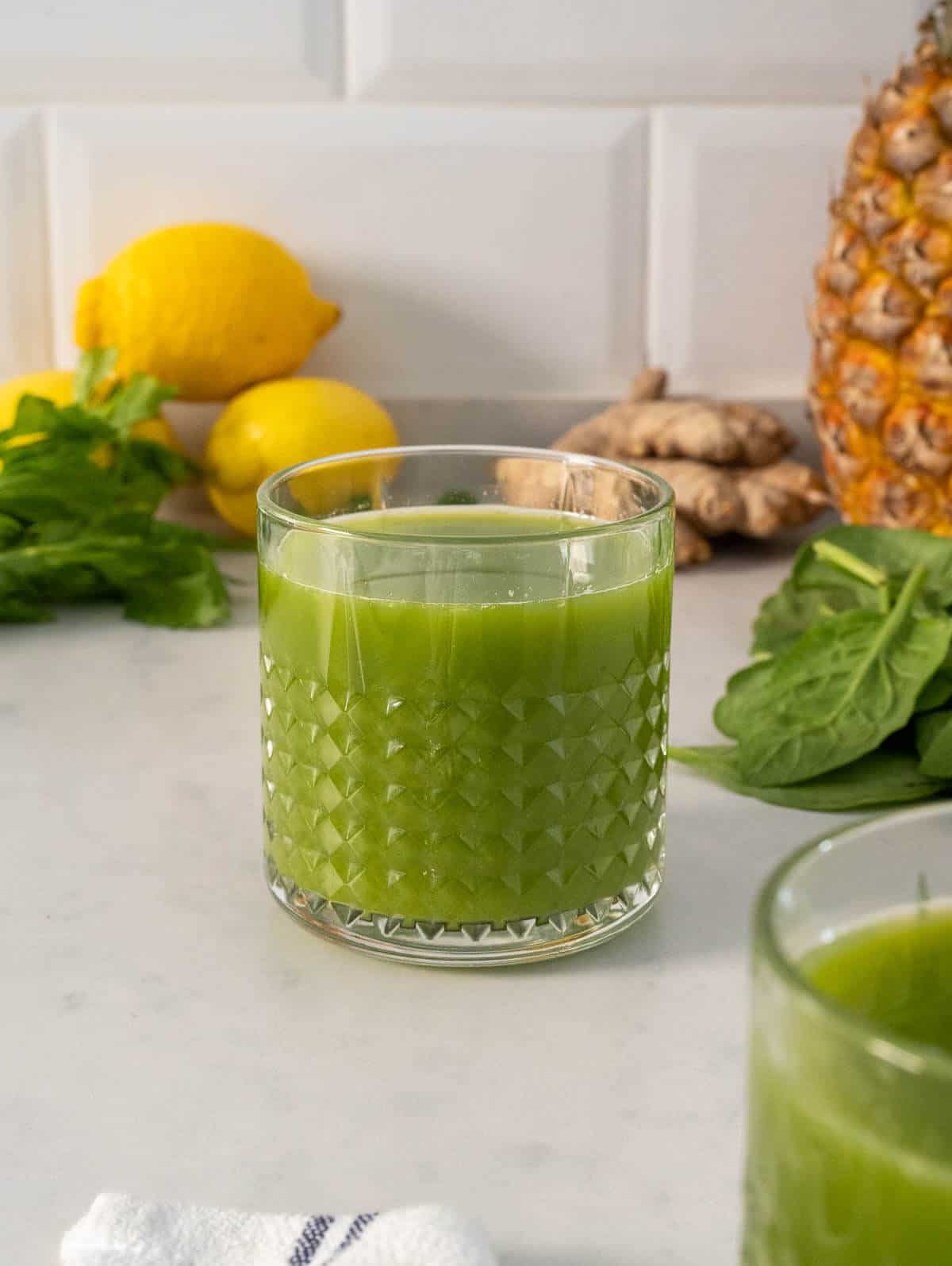 one glass of pineapple ginger green juice with spinach and cucumber for weight loss.