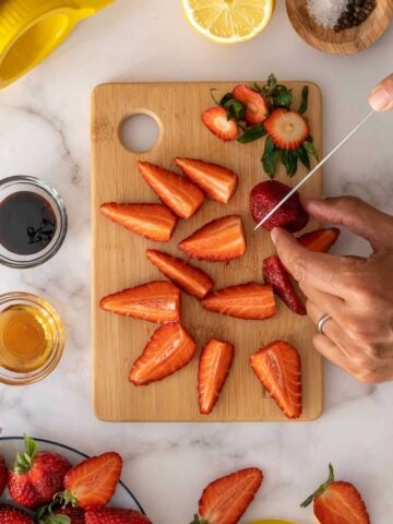 chopping fresh strawberries into quarters.