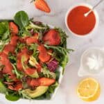 creamy strawberry balsamic dressing over a spinach and arugula salad featured.