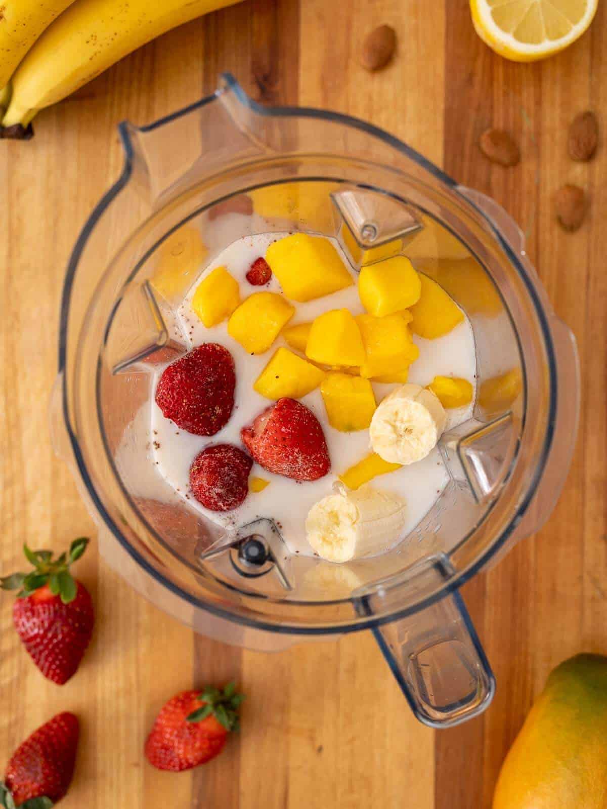 all ingredients for the strawberry mango banana smoothie in the blender's jar.