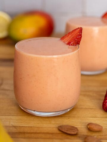 two glasses of strawberry banana mango smoothie featured.