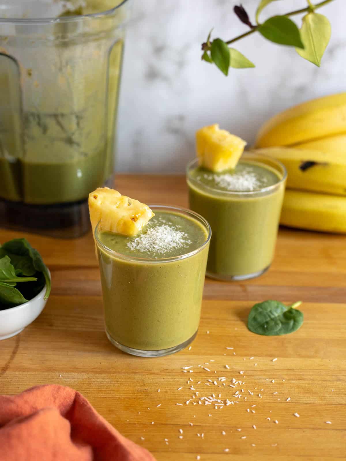 garnished glasses of smoothie with the blander's jar behind.