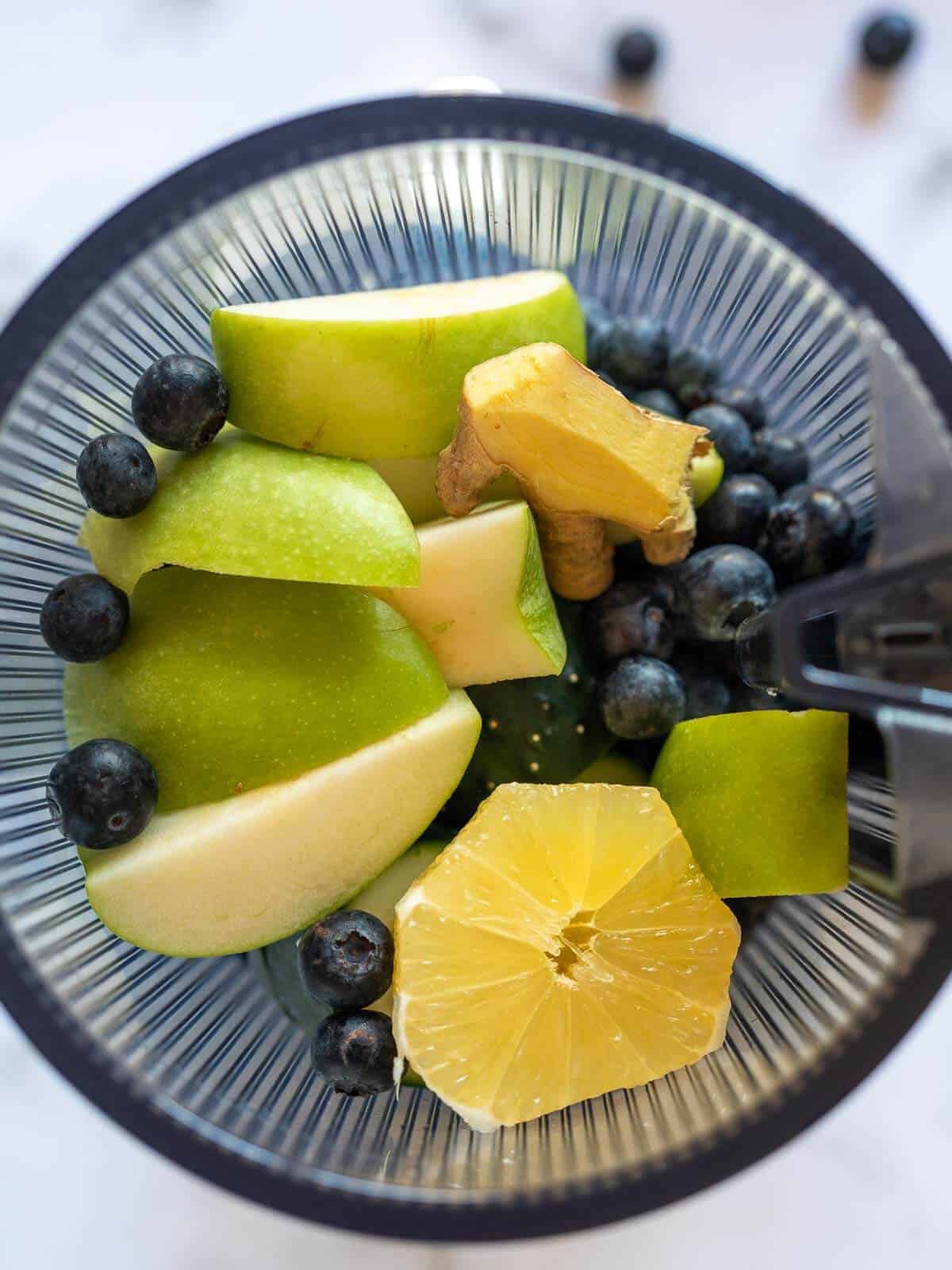 chopped fruits and vegetables inside of the juicer vase.