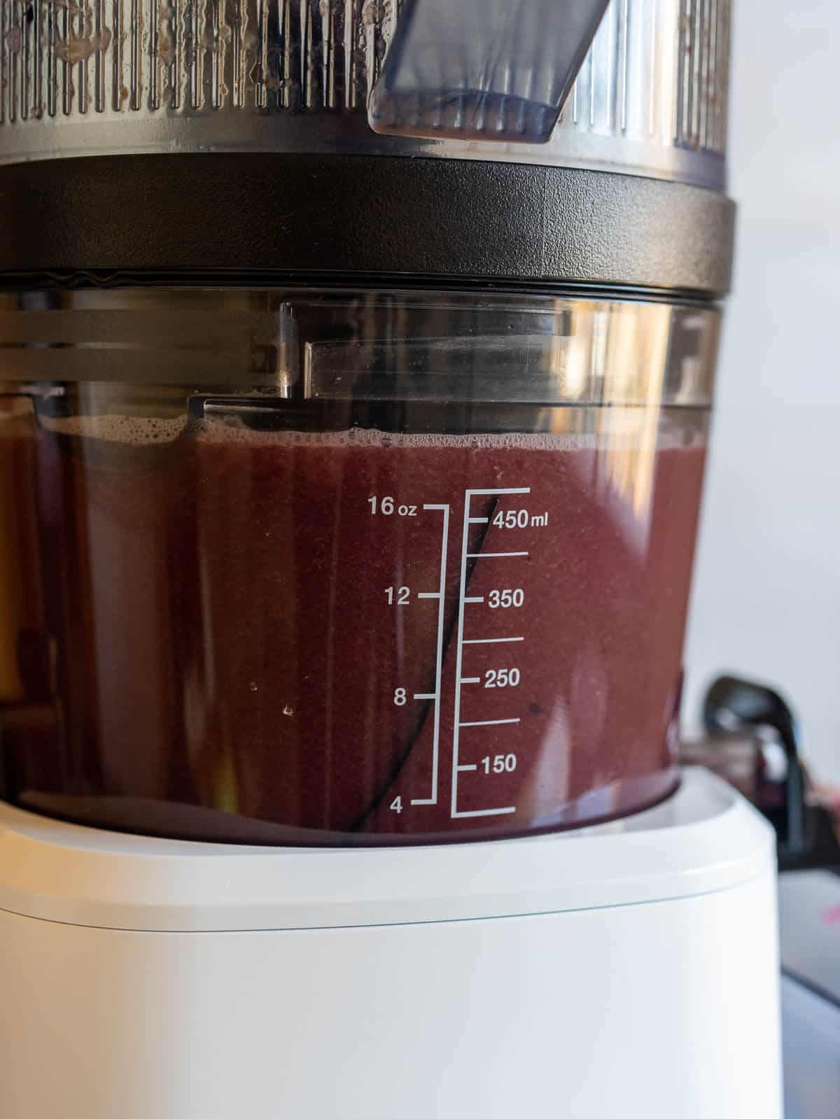 juicer container with blueberry juice before pouring it.