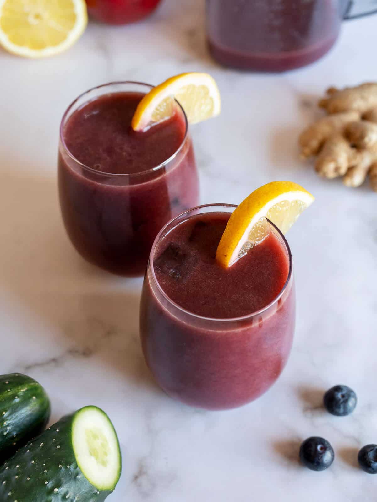 two glasses of organic blueberry juice with a lemon wedge.