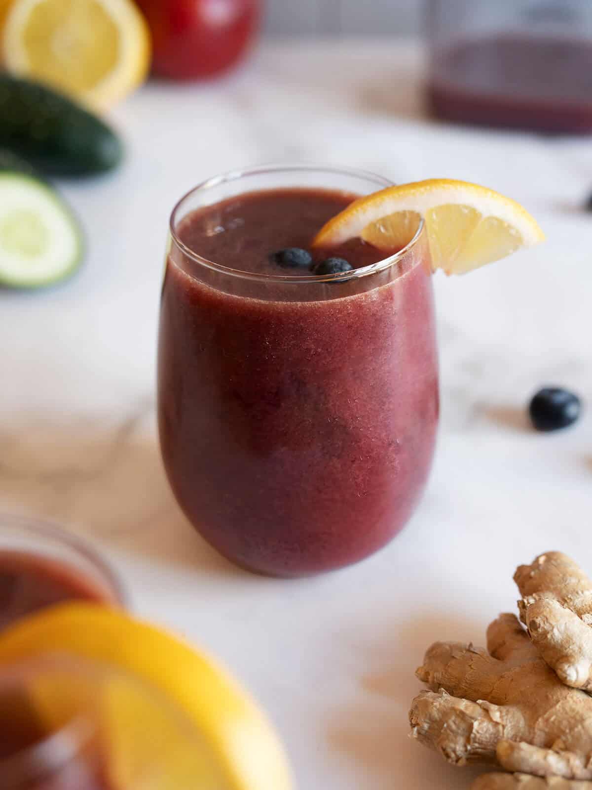 glass of organic blueberry juice garnished with a lemon wedge.