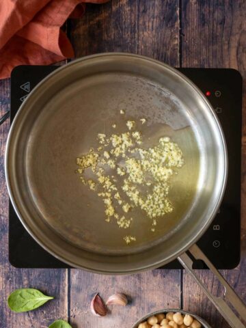 adding chopped garlic to the heated olive oil.