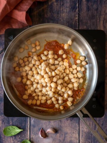 adding chickpeas to the spiced garlic.
