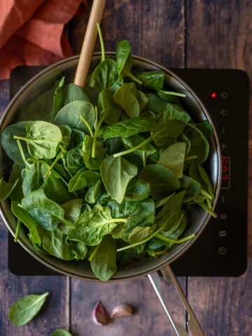 adding spinach to the saucepan.