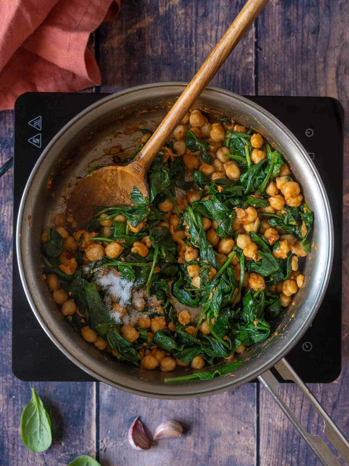 stirring wilted spinach with chickpeas.