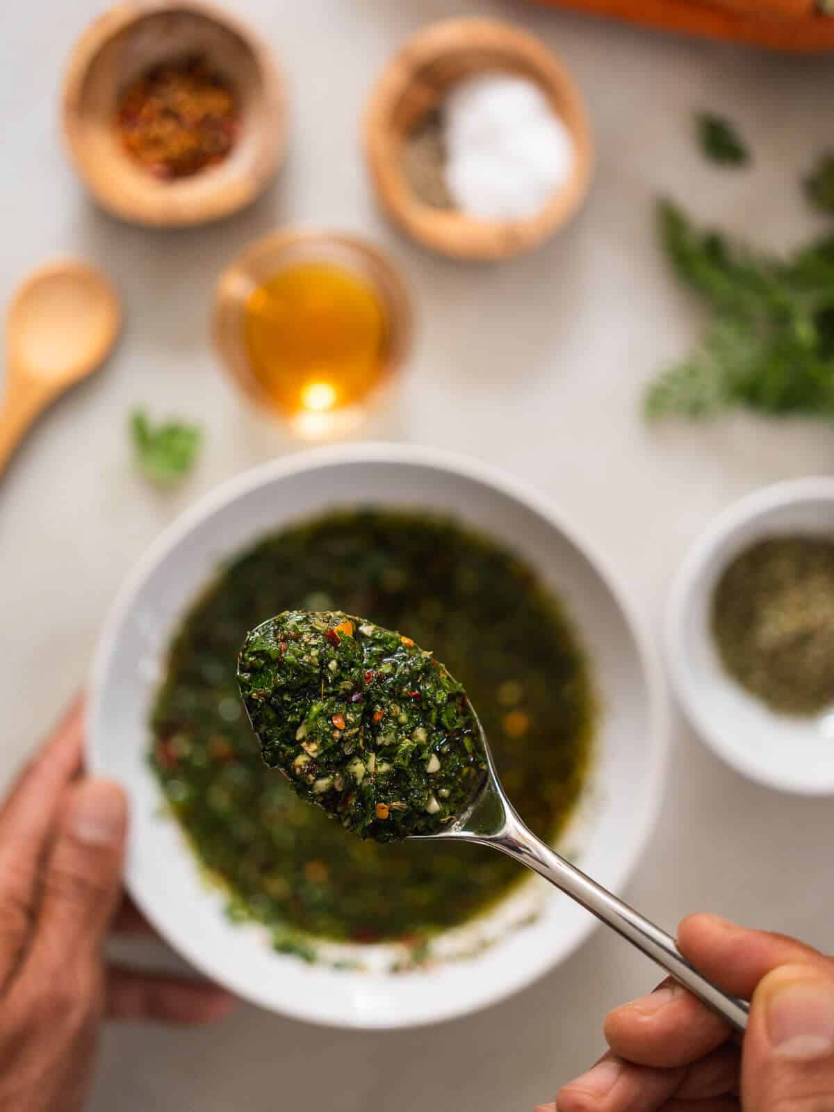 spoon showing the mixed carrot top chimichurri's texture.