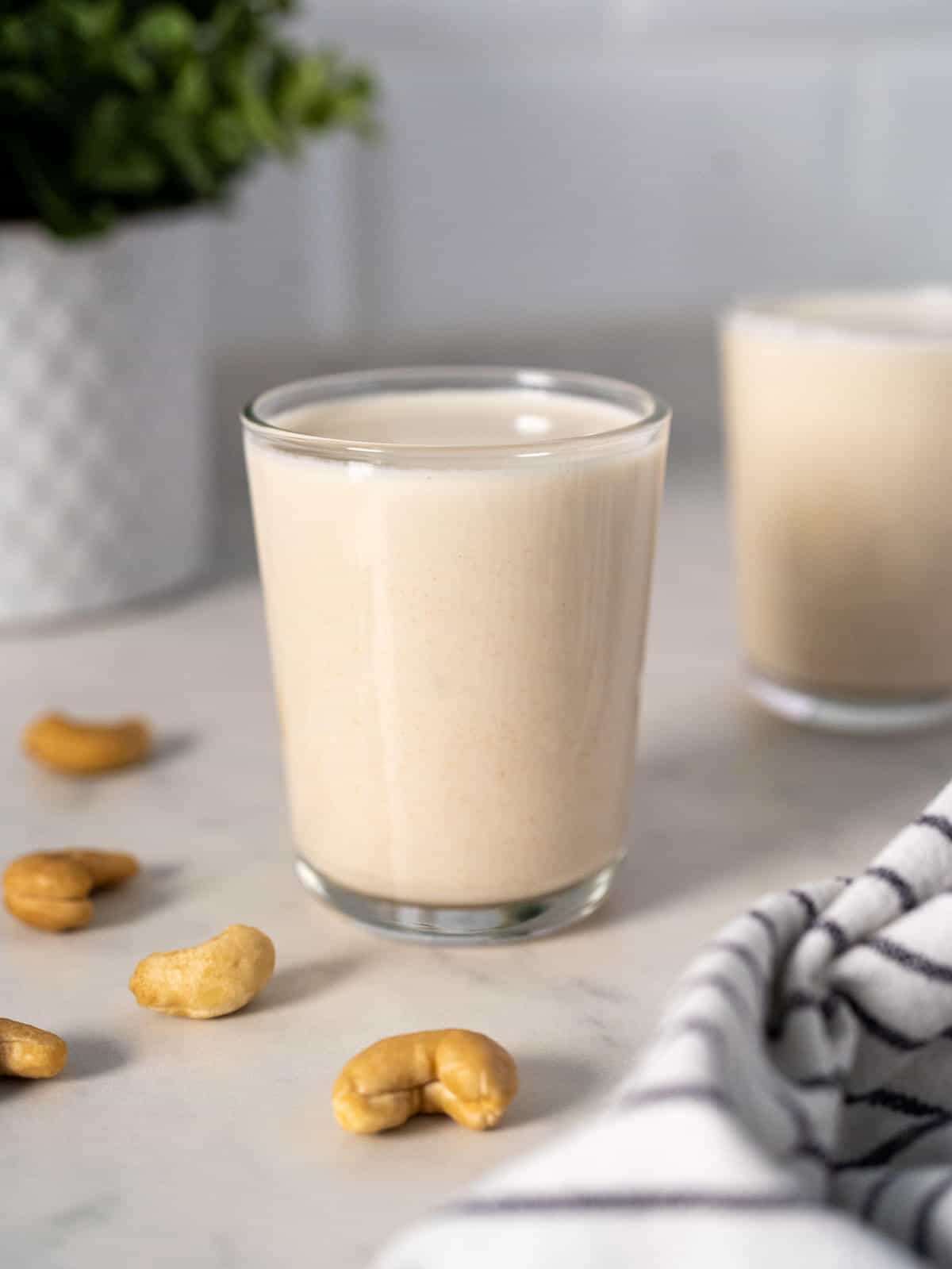 A glass of cashew milk with a bowl of cashews beside it.