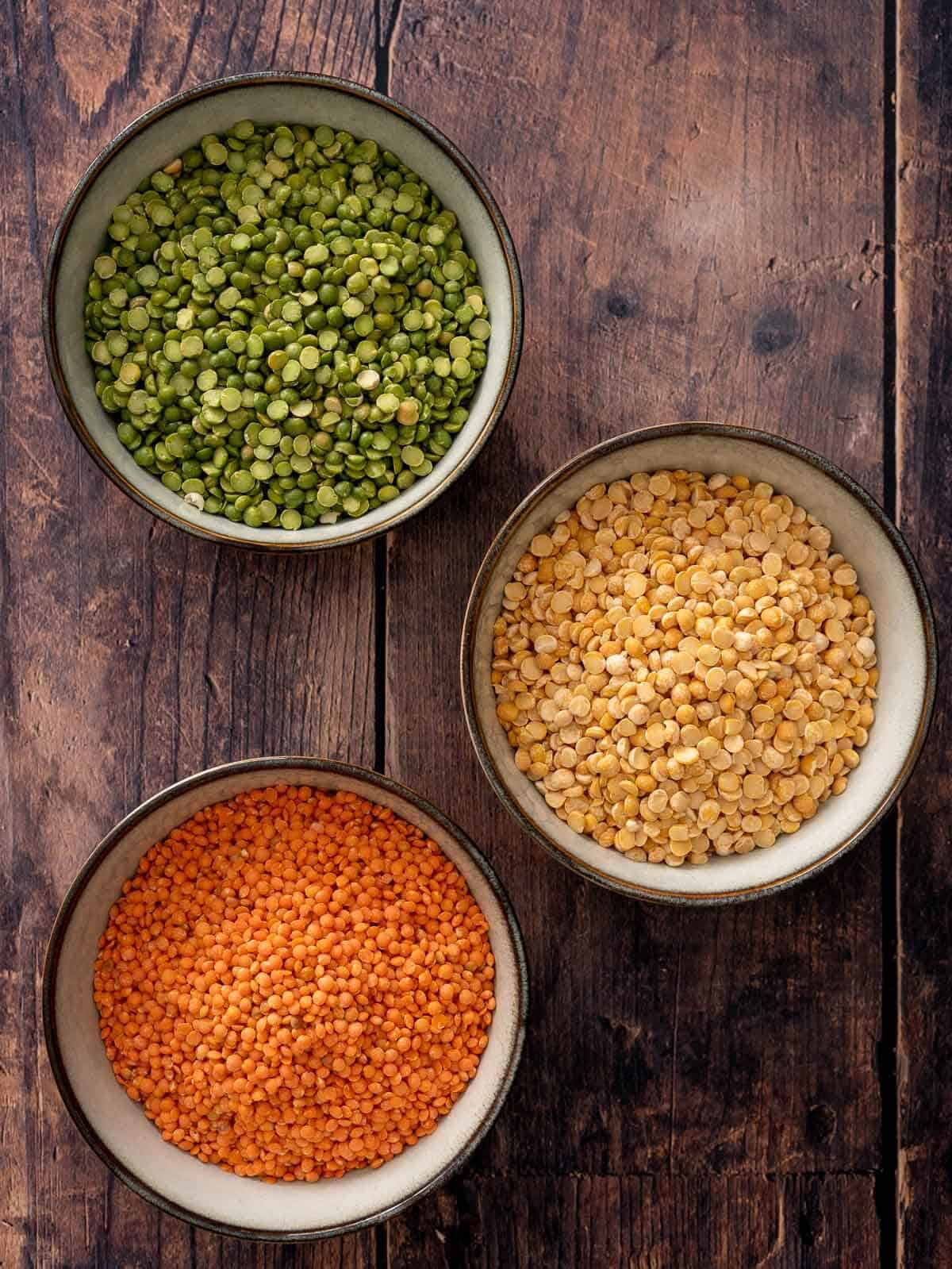 three bowls with green peas, yellow peas, and red lentils.