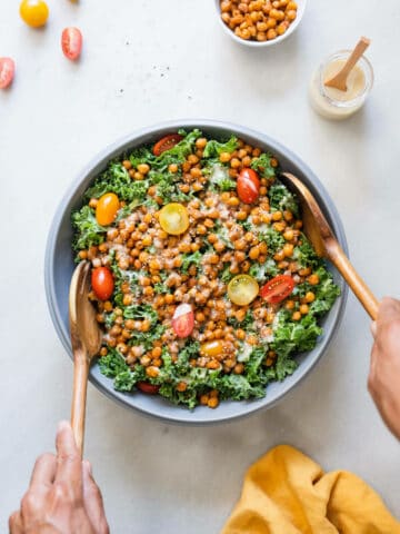 tossing kale salad with crispy chickpeas and maple tahini dressing.