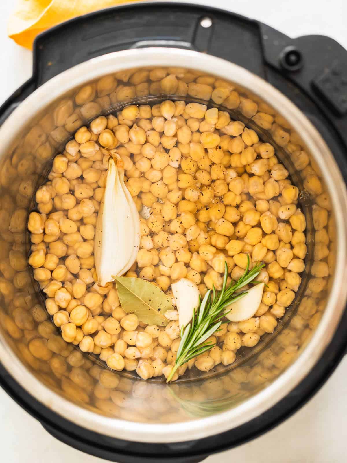 chickpeas in the instant pot with water, onion, garlic, and herbs.