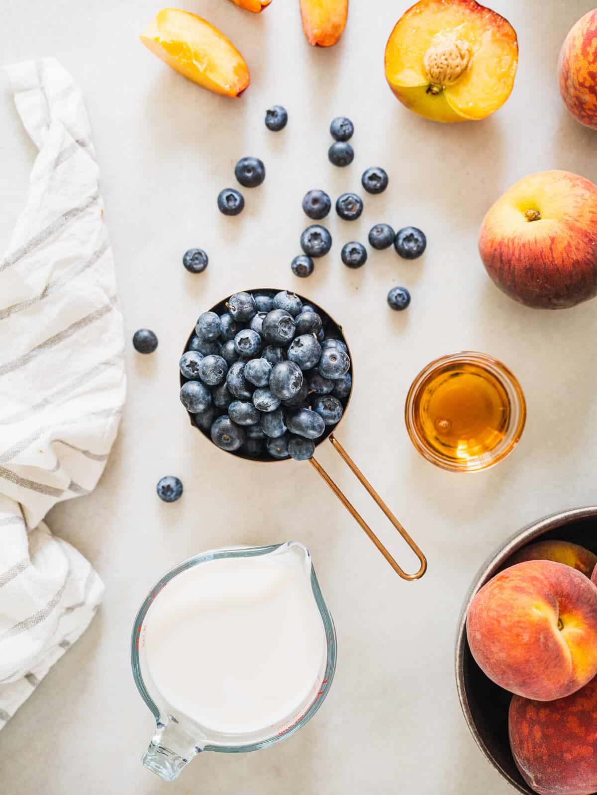 ingredients to make a peach blueberry smoothie on a table.