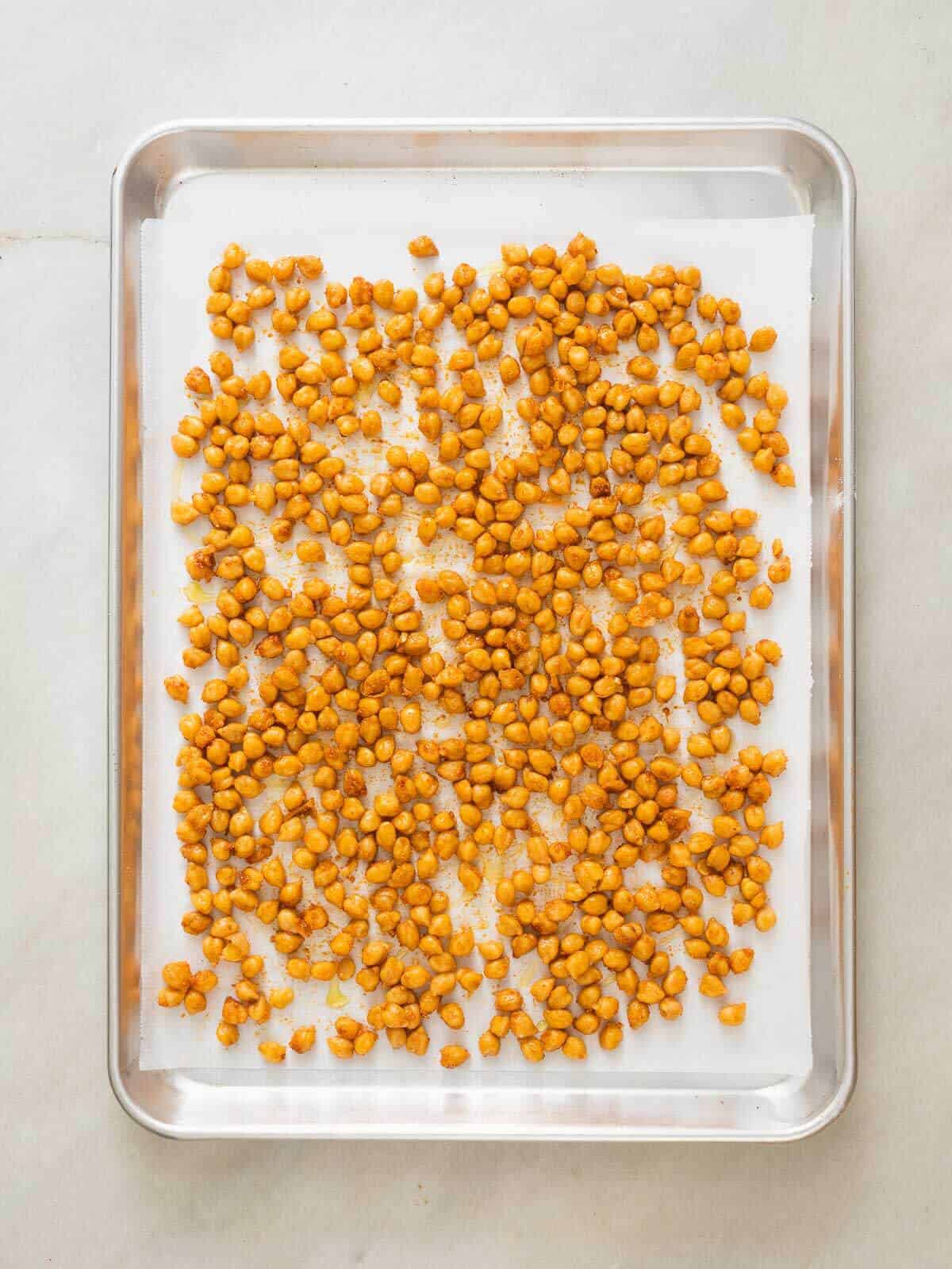 seasoned chickpeas spread on a lines baking sheet.