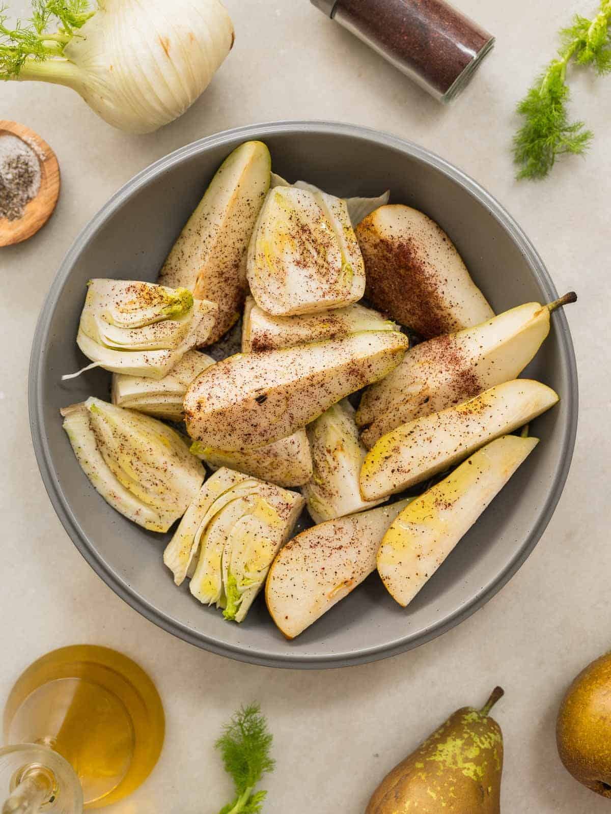 fennel and pear slices in bowl seasoned with sumac and olive oil.