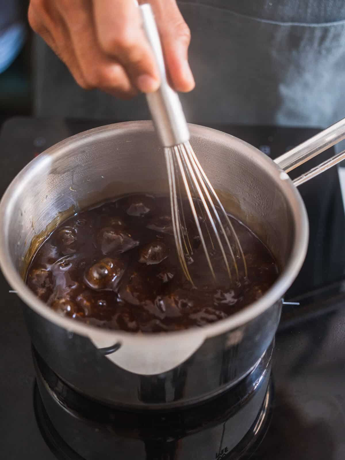 whisking simmering thickened teriyaki sauce.