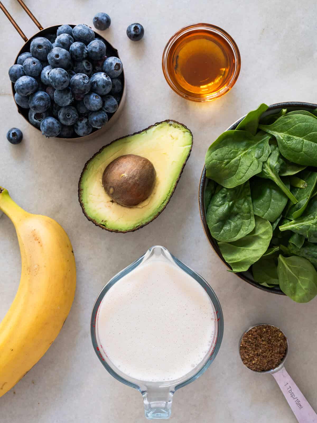 ingredients to make an avocado blueberry smoothie with spinach and banana.
