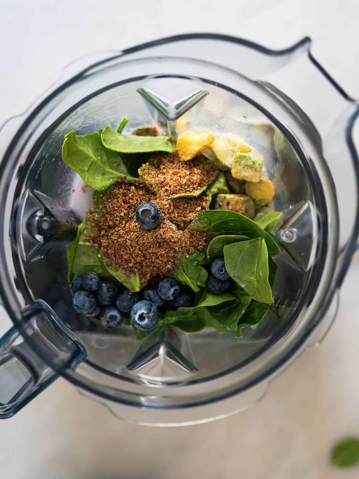 all the blueberry spinach smoothie ingredients in the blender's vase.