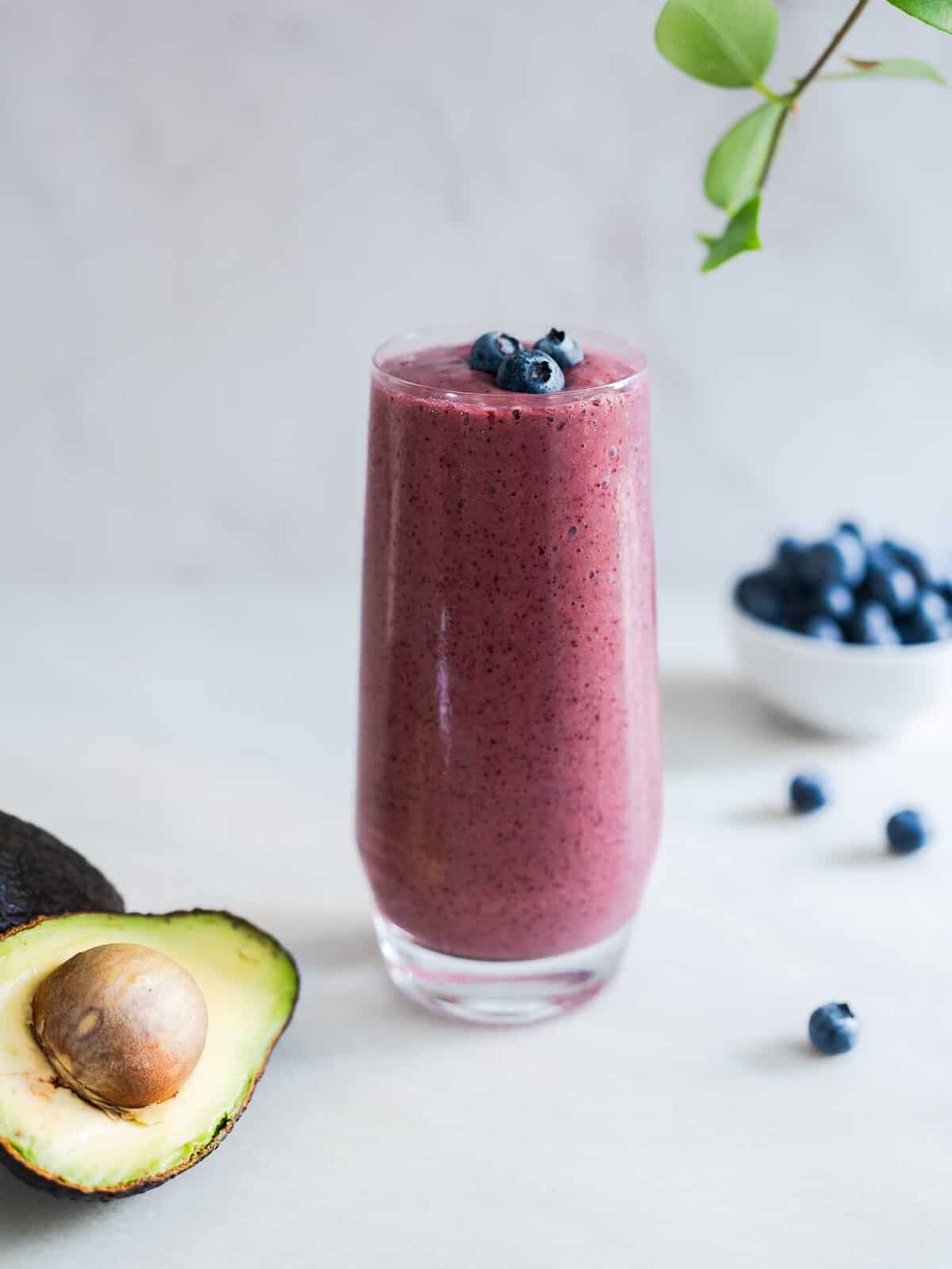 a glass of blueberry avocado smoothie with spinach.