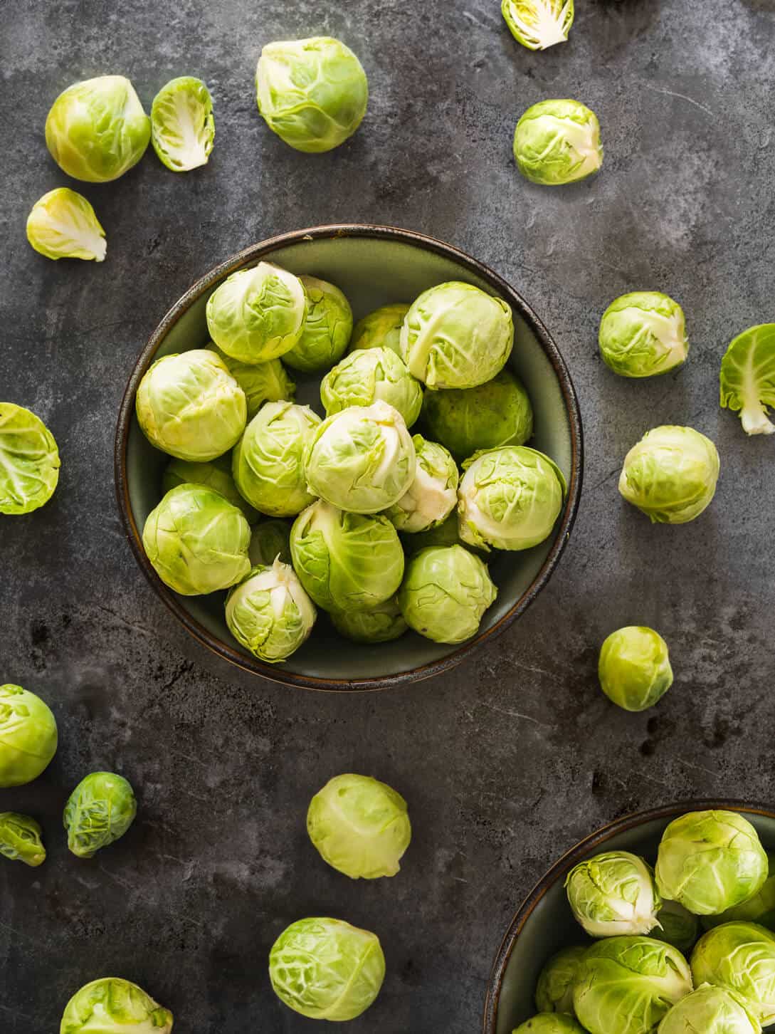 Brussels sprouts in a bowl and spread on a table.