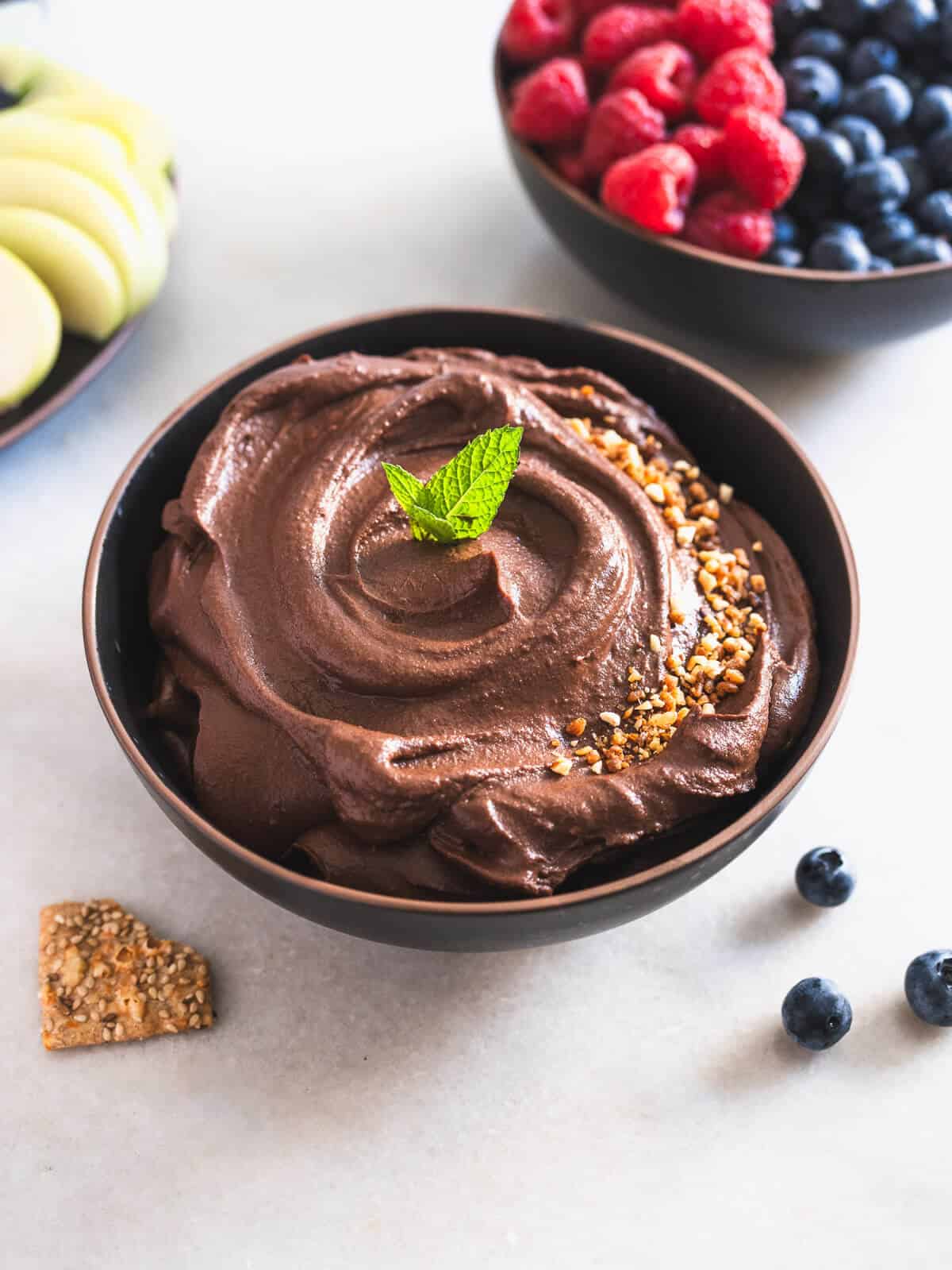 dark chocolate hummus served with apple slices blueberries and raspberries.