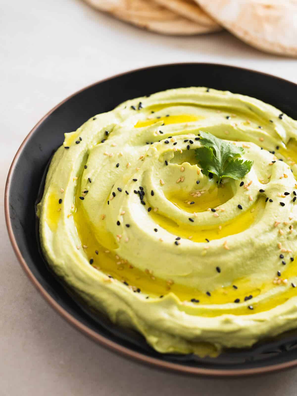 green edamame dip served in a dark plate.