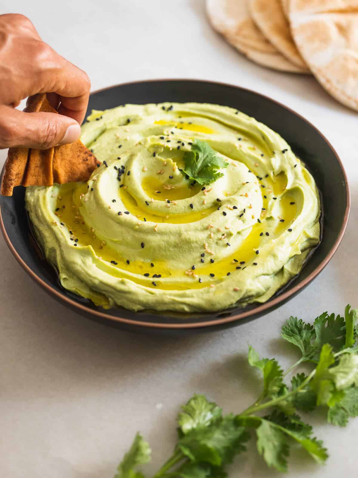 scooping hummus with a pita chip.