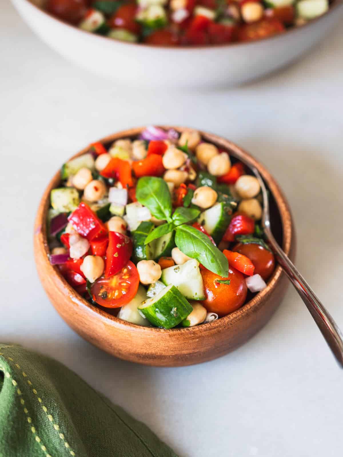 wooden bowl with mediterranean salad and a scooping spoon.