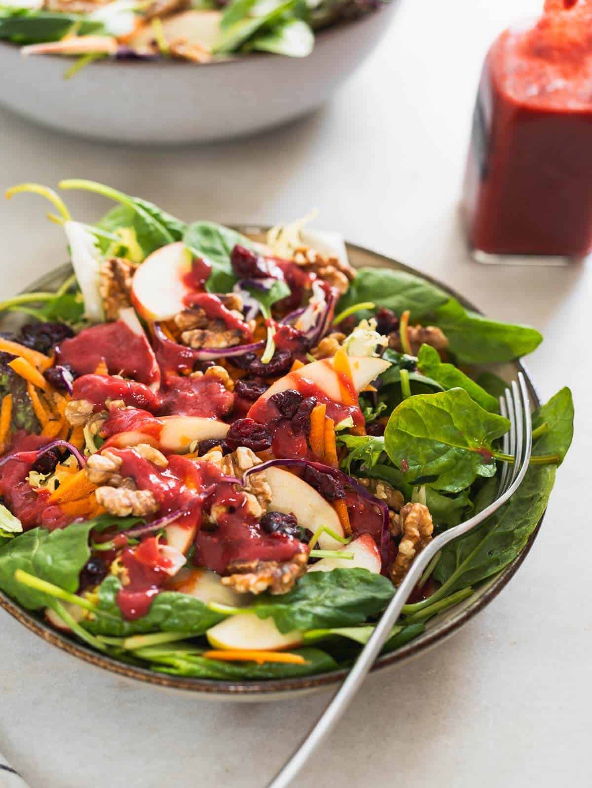 Spinach Apple Walnut Salad topped with raspberry dressing.