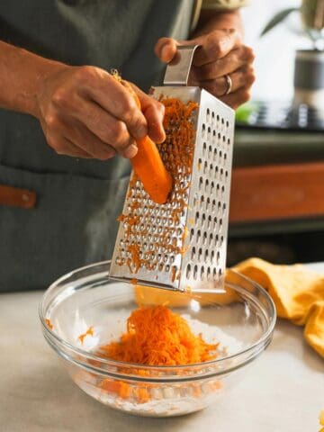 grating carrots on a box grater over the wet ingredients.
