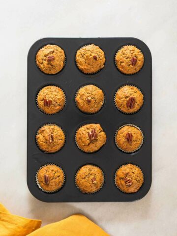 freshly bakes carrot banana muffins in muffin tin.