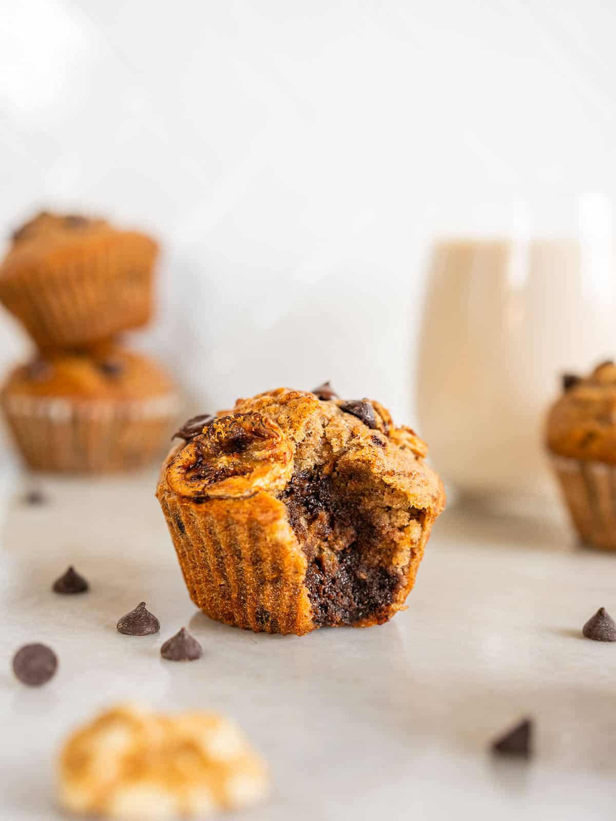 Bitten muffin with a glass of plant-based milk on the side.