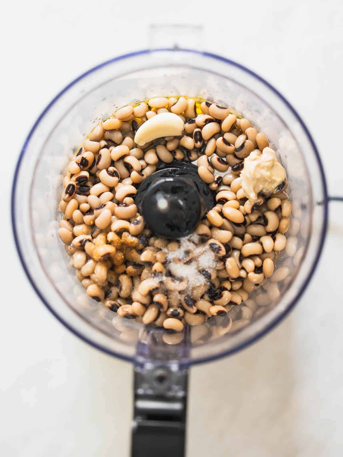 black eyed peas hummus, garlic, olive oil, salt, and cumin seen from above in food processors vase.