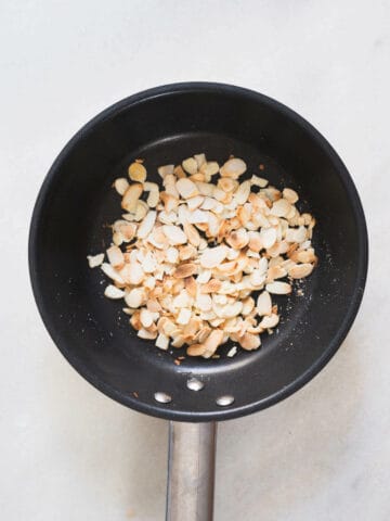 toasting sliced almonds on a skillet.