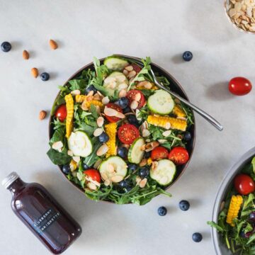 spinach and arugula salad with blueberry in a serving bowl featured.