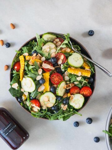 spinach and arugula salad with blueberry in a serving bowl featured.